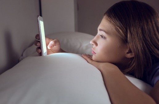 teenager on their phone while in bed